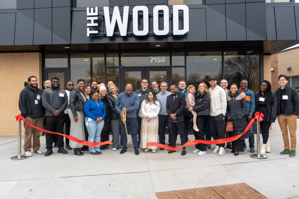 People standing in front of a building doing a ribbon cutting.